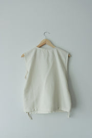 Back view of sleeveless hemp-cotton summer top on hanger, natural fiber clothing with clean lines and relaxed silhouette.
