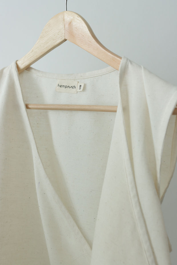 Minimalist hemp and cotton wrap vest hanging on wooden hanger, v-neck front and light texture for eco-friendly daily wear