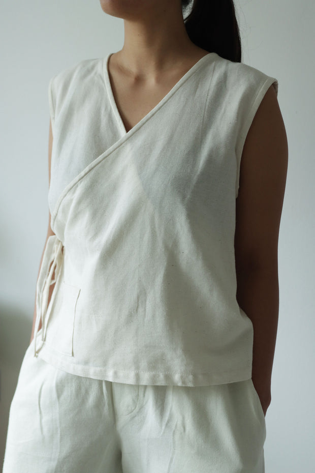 Woman wearing sleeveless hemp cotton wrap top with v-neck and adjustable waist. Ethical, lightweight summer clothing for minimalist style