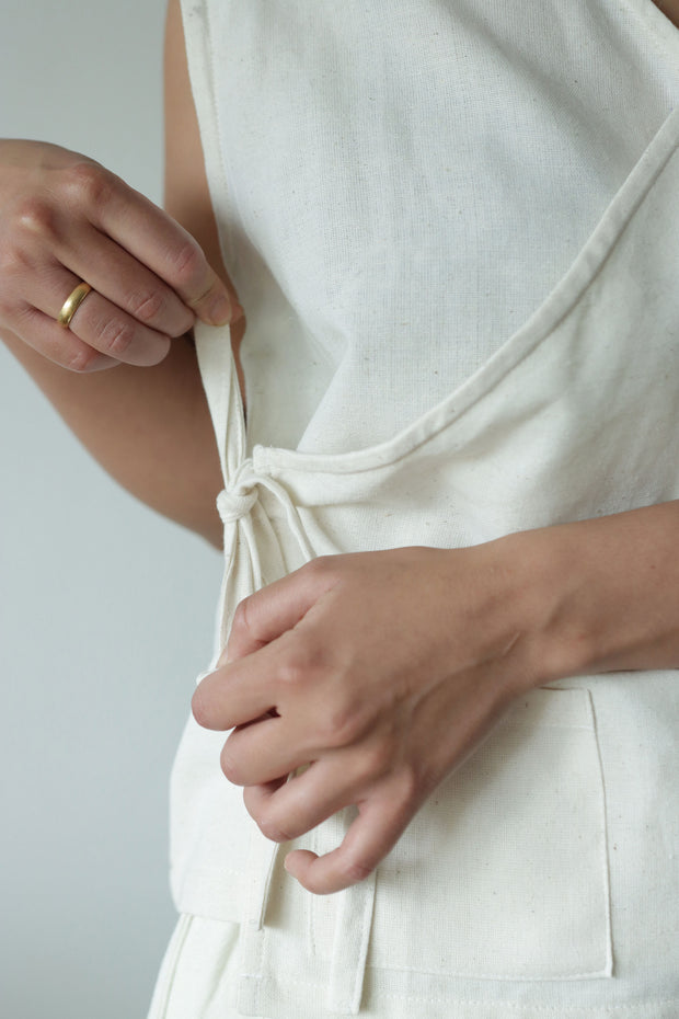 Detail of a waist tie being adjusted on a natural hemp and cotton wrap top, showcasing its handmade functionality and comfort