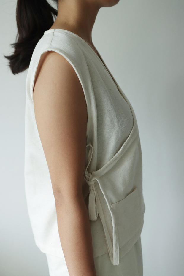 Woman wearing natural fiber wrap top in profile view, sleeveless, airy, and ethically made for breathable summer comfort