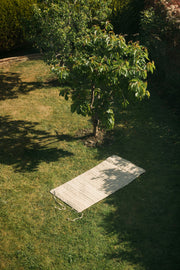 Aerial view of the yoga mat laid flat on the grass under a tree.