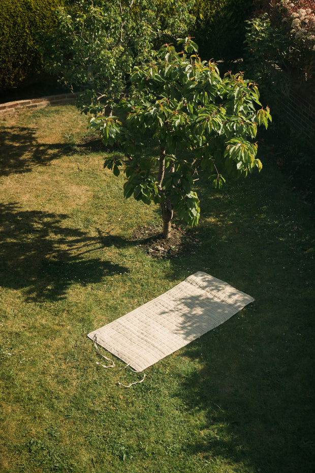 Aerial view of the yoga mat laid flat on the grass under a tree.