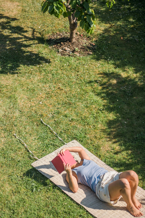 Person lying on a Natural Hemp Yoga Mat under a tree in the sun.