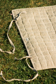 Yoga mat rolled out on grass, showing cotton tie straps for easy rolling.
