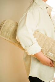 Person holding the rolled-up hemp yoga mat against their chest.