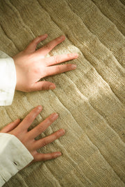 Close-up of hands touching the textured surface of the hemp yoga mat.