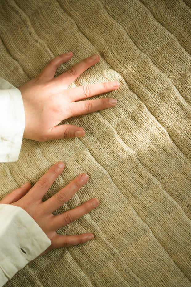 Close-up of hands touching the textured surface of the hemp yoga mat.