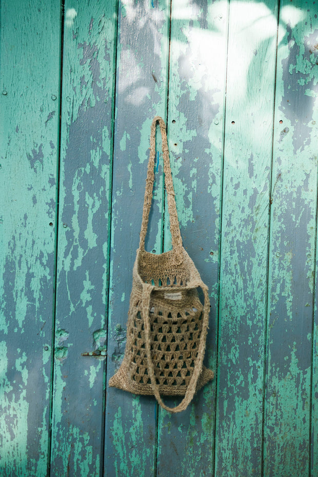 A stylish and eco-friendly hemp shoulder bag in a knitted jhola design, showcasing its natural beige tone with a soft, textured finish. 